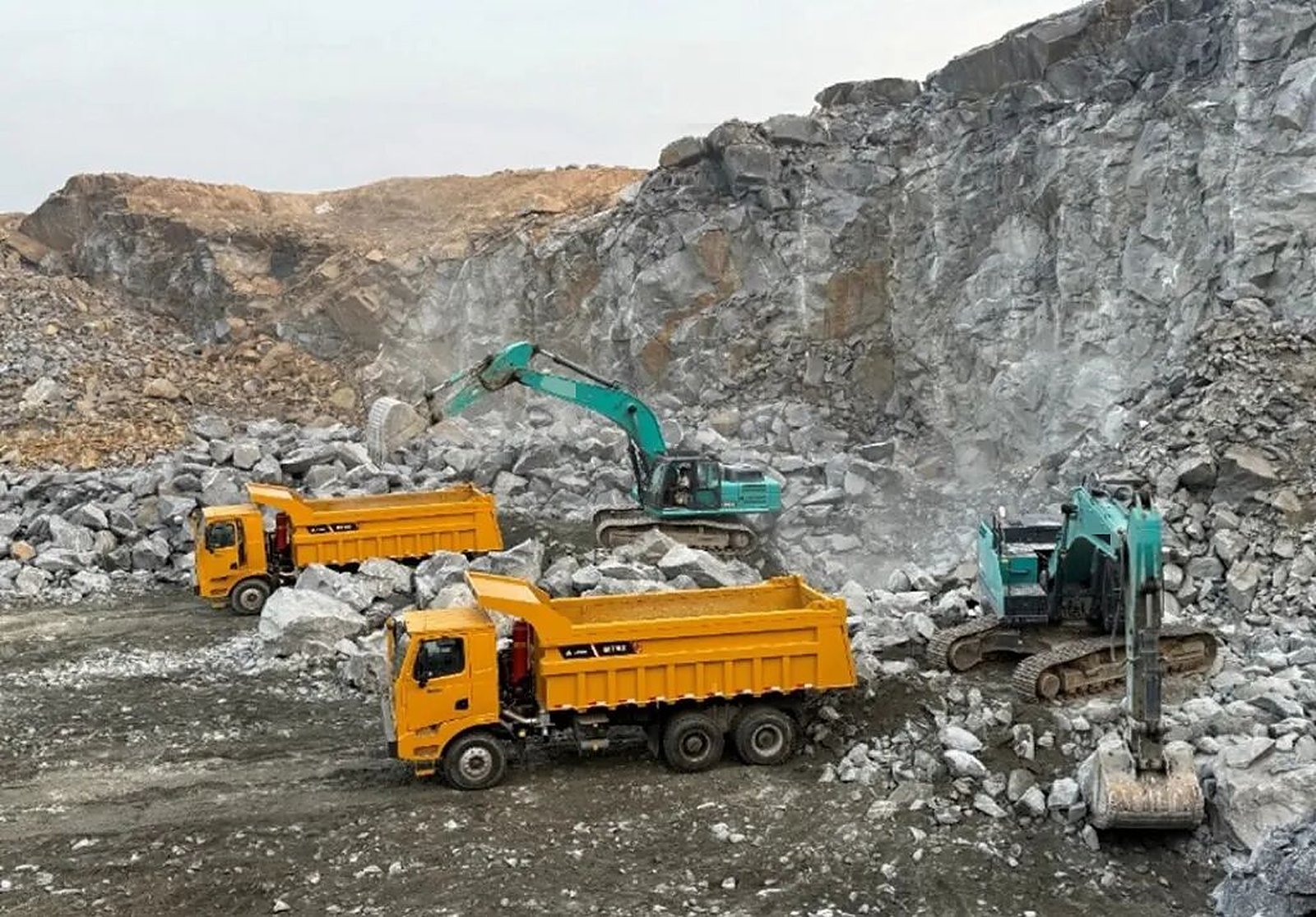 Camiones mineros LGMG cargados por excavadoras en el frente de una cantera